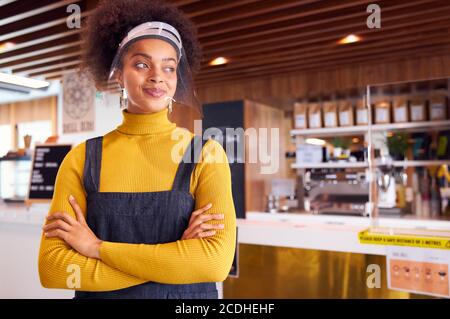 Weibliche afrikanische Café-Besitzer trägt Gesichtsmaske stehen in Vorderseite des Counter Stockfoto
