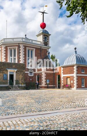 Die Grenwich Prime Meridian Linie kreuzt die Kopfsteinpflaster vor dem Flamsteed House am Royal Observatory Greenwich. Unter der Wetterfahne ist Stockfoto