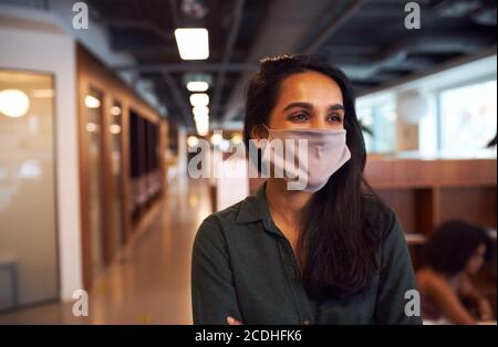 Porträt der modischen indischen Geschäftsfrau trägt Gesichtsmaske im Büro. Stockfoto