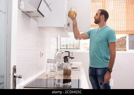 Mann, der einen Topf mit Makkaroni aus der Küche abholt Speisekammer Stockfoto