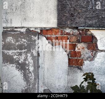 Detail eines Abbruchhauses mit abgebrochtem Putz und erkennbar Rote Steine darunter Stockfoto