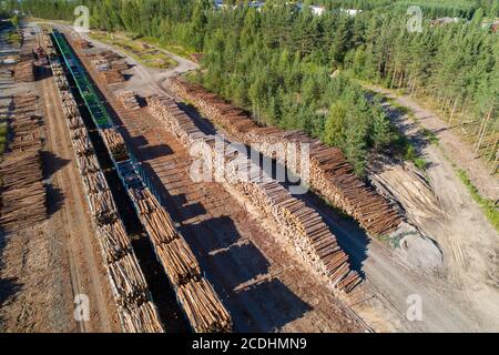 Luftaufnahme eines Eisenbahnhofes mit Holzpfählen und Eisenbahnwaggons, die mit Holz für den Transport im Sommer in Finnland beladen sind Stockfoto