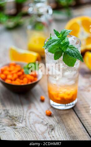 Sanddorneis Limonade mit Orangen. Früchte und Beeren im Freien auf einem Holztisch. Entgiftungsgetränke. Selektiver Fokus, Kopierbereich Stockfoto