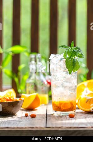 Sanddorneis Limonade mit Orangen. Früchte und Beeren im Freien auf einem Holztisch. Entgiftungsgetränke. Selektiver Fokus, Kopierbereich Stockfoto