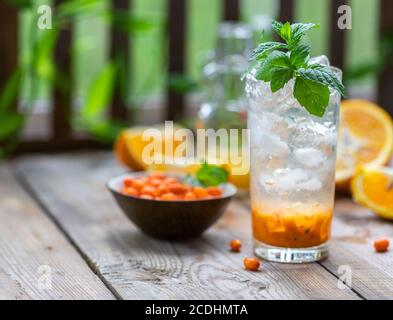 Sanddorneis Limonade mit Orangen. Früchte und Beeren im Freien auf einem Holztisch. Entgiftungsgetränke. Selektiver Fokus, Kopierbereich Stockfoto