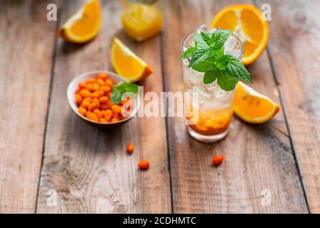 Sanddorneis Limonade mit Orangen. Früchte und Beeren im Freien auf einem Holztisch. Entgiftungsgetränke. Selektiver Fokus, Kopierbereich Stockfoto