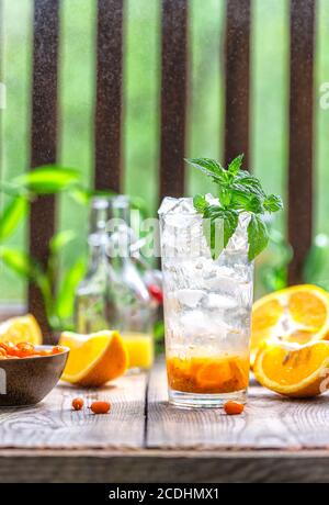 Sanddorneis Limonade mit Orangen. Früchte und Beeren im Freien auf einem Holztisch. Entgiftungsgetränke. Selektiver Fokus, Kopierbereich Stockfoto