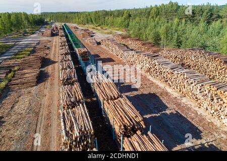 Luftaufnahme eines Eisenbahnhofes mit Holzpfählen und Eisenbahnwaggons, die mit Holz für den Transport im Sommer in Finnland beladen sind Stockfoto