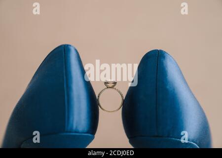 Verlobungsring der Braut mit einem Edelstein zwischen blauen Schuhen. Stockfoto