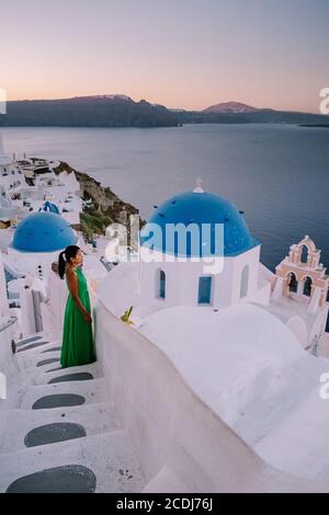 Sonnenuntergang auf der Insel Santorini Griechenland, schönes weiß getünchtes Dorf Oia mit Kirche und Windmühle während Sonnenuntergang Frau auf Luxusurlaub Griechenland Stockfoto