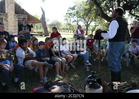 Stonewall, TX, 2007. Oktober: Afroamerikanischer Mann, der als Buffalo Soldier gekleidet ist, beschreibt den Alltag schwarzer Soldaten an der Grenze zu Texas in den 1860er Jahren bis hin zu Jungen und Mädchen der fünften Klasse auf einem Schulausflug zum Johnson-Siedlungsabschnitt des Lyndon B. Johnson National Historical Park in Johnson City, Texas. Die Studenten erfahren, wie die frühen Anglo-Siedler, einschließlich des Urgroßvaters der LBJ, in den 1860er Jahren an der texanischen Grenze lebten. ©Bob Daemmrich Stockfoto