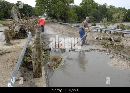 Marble Falls, TX 28. Juni 2007: Chris Pounds von der Marble Falls Street & Bridge Dept. Bewegt einen Baumstamm, der gegen eine Stadtbrücke gestapelt ist, während die Säuberung nach einer Sturzflut am Vortag fortgesetzt wird. ©Bob Daemmrich Stockfoto