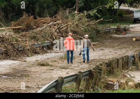 Marble Falls, TX 28. Juni 2007: Cory Hisey (l) und Chris Pounds von der Stadt Marble Falls gehen an einem Trümmerhügel auf einer Brücke in der Innenstadt vorbei, nachdem in wenigen Stunden 19 cm Regen gefallen war, Verursacht Sturzfluten und Schäden in Millionenhöhe entlang eines Baches, der durch ein Industriegebiet in der Stadt fließt. ©Bob Daemmrich Stockfoto