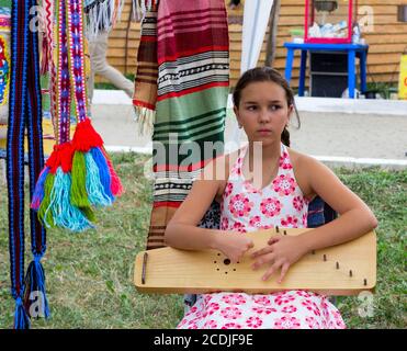 Adygea, Russland - 19. August 2017: Trauriges Mädchen, das auf der Harfe beim Festival von Käse Adyghe in Adygea Musik spielt Stockfoto