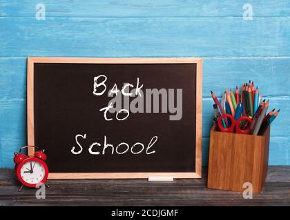 Tafel mit Aufschrift 'Back to School', Wecker, Etui mit Stiften Stockfoto