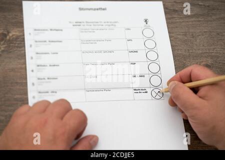 Brilon, Nordrhein-Westfalen/ Deutschland: 27. August 2020: Ein Mann sitzt vor einer Wahlurne für die Wahl. Deutscher Parteiname und ein fiktiver Deutscher Stockfoto