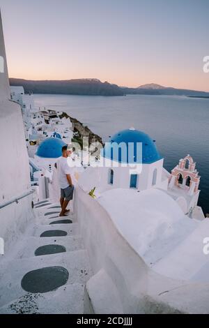 Sonnenuntergang auf der Insel Santorini Griechenland, wunderschönes weiß getünchtes Dorf Oia mit Kirche und Windmühle während des Sonnenuntergangs, junge Männer auf Luxusurlaub Stockfoto