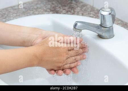 Hygienekonzept Reinigung der Hand und Händewaschen. Ein Mann wäscht seine Hände mit Seife und Wasser im Becken. Stockfoto