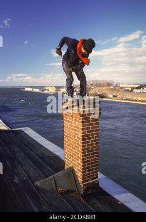 OSWEGO, NEW YORK, USA - Schornsteinfeger-Waagen am Schornstein des Gebäudes am Oswego River, März 1985 Stockfoto