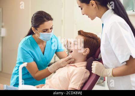 Zahnarzt und Assistent überprüfen die Zähne eines Jungen Kind in einer Zahnklinik. Stockfoto