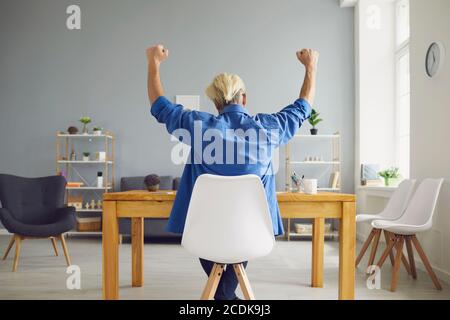 Nicht erkennbarer Hipster sitzt am Tisch und zeigt ja Geste Stockfoto