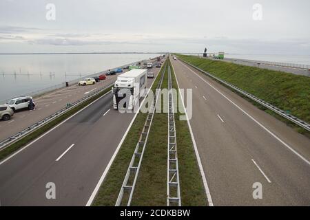 Autobahn mit Verkehr auf dem Afsluitdijk in den Niederlanden, einem großen Damm und Damm, der den Waddenzee vom Ijsselmeer trennt. Bewölkt, neblig. Stockfoto