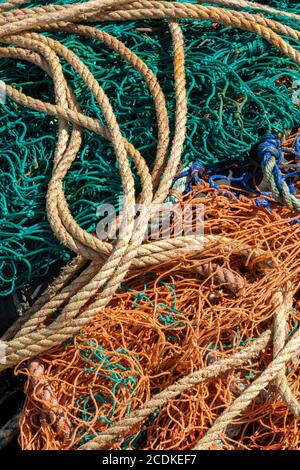 Ein Gewirr von verknoteten Leitungen und Drähten mit farbigen Seilen und Netzen an einem Kai. Stockfoto