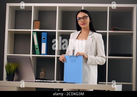 Junge Geschäftsfrau hält einen Ordner, Brünette in einem Anzug Stockfoto