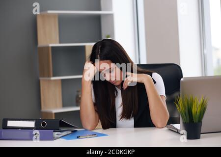 Verärgerte Geschäftsfrau, die am Arbeitsplatz im Büro sitzt Stockfoto