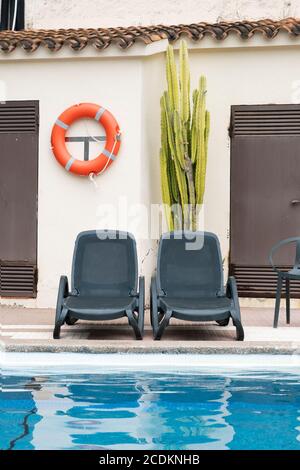 Leere Sonnenliegen neben einem Swimmingpool in einem leeren Hotel wegen Coronavirus-Pandemien. Rezession in der Tourismuswirtschaft. Stockfoto