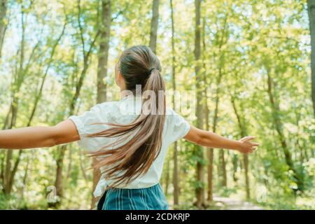 Glückliche Frau im Wald mit offenen Armen von hinten atmen saubere Luft. Umwelt, keine Verschmutzung gesunde natürliche Lebensweise. Freier Geist im Stockfoto