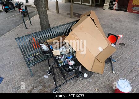 Eine obdachlose Person, mit Habseligkeiten in einem Einkaufswagen, schläft auf einer Metallbank unter Pappe bei 10th St. und Congress Ave. Früh am Morgen in der Innenstadt von Austin im August 2020. ©Bob Daemmrich Stockfoto
