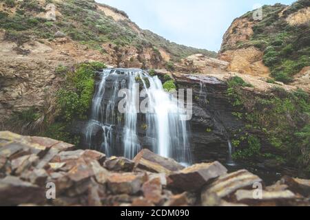 Frisches Wasser fließt an den Alamere Falls in Point Reyes, Kalifornien, in dunklem Fels. Stockfoto