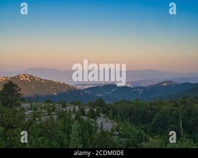 Eine schöne Landschaft irgendwo in Österreich, Europa. Ein Wald im Vordergrund und riesige Berge im Hintergrund. Ein schöner, bläulicher Himmel. Stockfoto