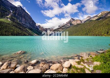 Lake Louise im Banff National Park, ab. Der Blick auf den türkisfarbenen See, umgeben von felsigen, von Gletschern bedeckten Bergen. Die Felsen im Vordergrund. Stockfoto