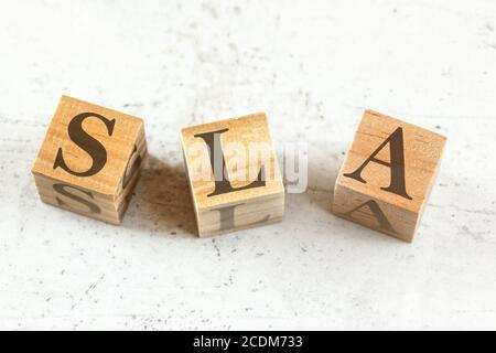 Drei Holzwürfel mit den Buchstaben SLA (steht für Service Level Agreement) auf Whiteboard. Stockfoto