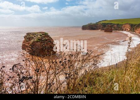 Wellen brechen an den Strand von Ladram Bay in der Nähe von Exmouth in South Devon, England, Großbritannien. Rote Sandsteinklippen, Teil der Jurassic Coast. Stockfoto