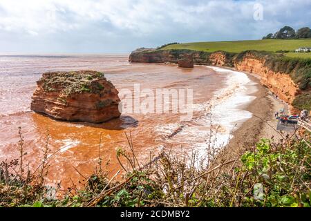 Wellen brechen an den Strand von Ladram Bay in der Nähe von Exmouth in South Devon, England, Großbritannien. Rote Sandsteinklippen, Teil der Jurassic Coast. Stockfoto