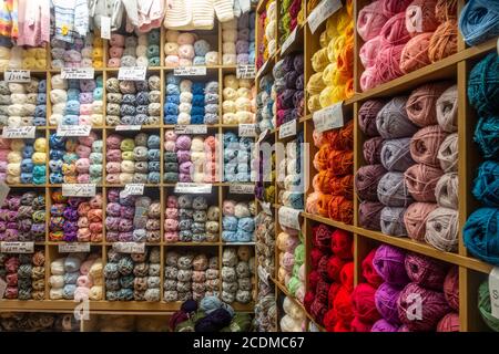 Bälle aus farbigem Strickwolle auf Regal im Verkauf in einem Geschäft angeordnet. Stockfoto