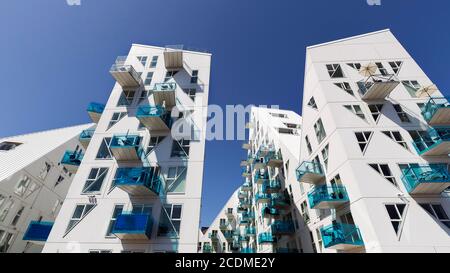 Weiße Wohnanlage mit türkisfarbenen Balkonen gegen einen blauen Himmel, zackige Gebäudeskulptur Isbjerget, Eisberg, moderne Architektur in der Stockfoto