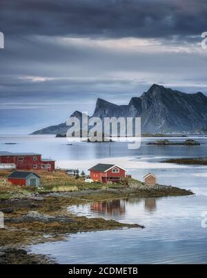 Bauernhaus am Fjord Rossoy Straumen, im Hintergrund das Meer und die Berge Hustinden und Bjoerntinden, Fredvang, Lofoten, Nordland, Norwegen Stockfoto