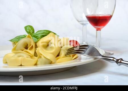 Tortelloni auf Teller mit Gabel und Glas Wein, Deutschland Stockfoto
