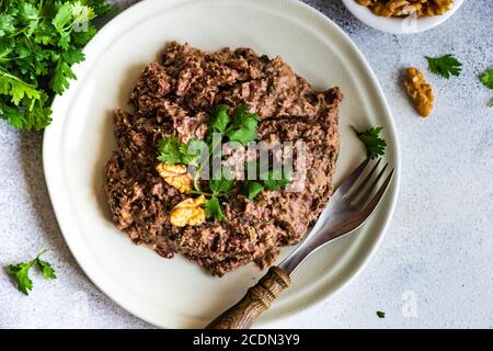 Traditionelle georgische Bohnengericht - LOBIO mit Walnuss, serviert in modernen strukturierten Keramikschale auf Stein Hintergrund mit Kopieplatz Stockfoto