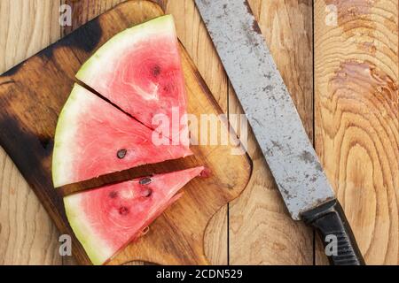 Wassermelone und altes Messer auf dem Tisch Stockfoto