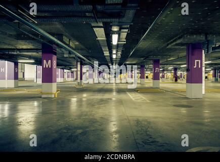 Tiefgarage innen, Neonlichter in dunklem Industriegebäude, moderne öffentliche Konstruktion Stockfoto