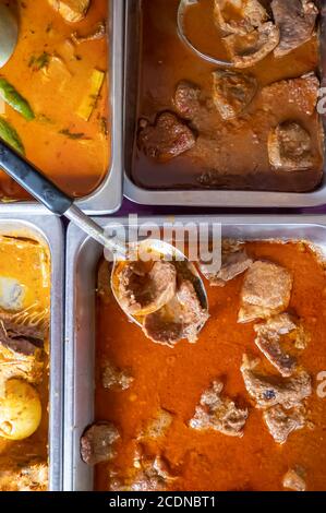 Authentisches Thai Street Food, Thai Traditionelles Essen mit verschiedenen Gewürzen und rotem heißem, rotem Curry auf Edelstahltabletts. Draufsicht. Nahaufnahme. Stockfoto