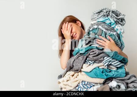 Schockierte kaukasische Hausfrau hält Haufen schmutziger Kleidung. Stockfoto