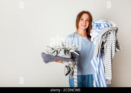 Kaukasische Hausfrau hält Haufen schmutziger Kleidung. Stockfoto