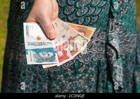 Eine Frau hält kolumbianische Pesos in der Hand. Hände auf dem Hintergrund des Kleides. Wirtschaftskrise Stockfoto