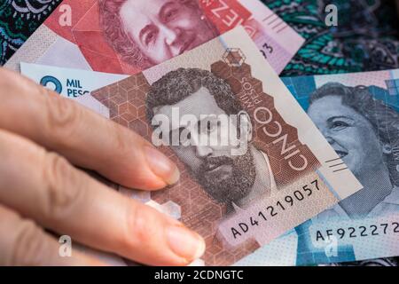 Eine Frau hält kolumbianische Pesos in der Hand. Hände auf dem Hintergrund des Kleides. Wirtschaftskrise Stockfoto